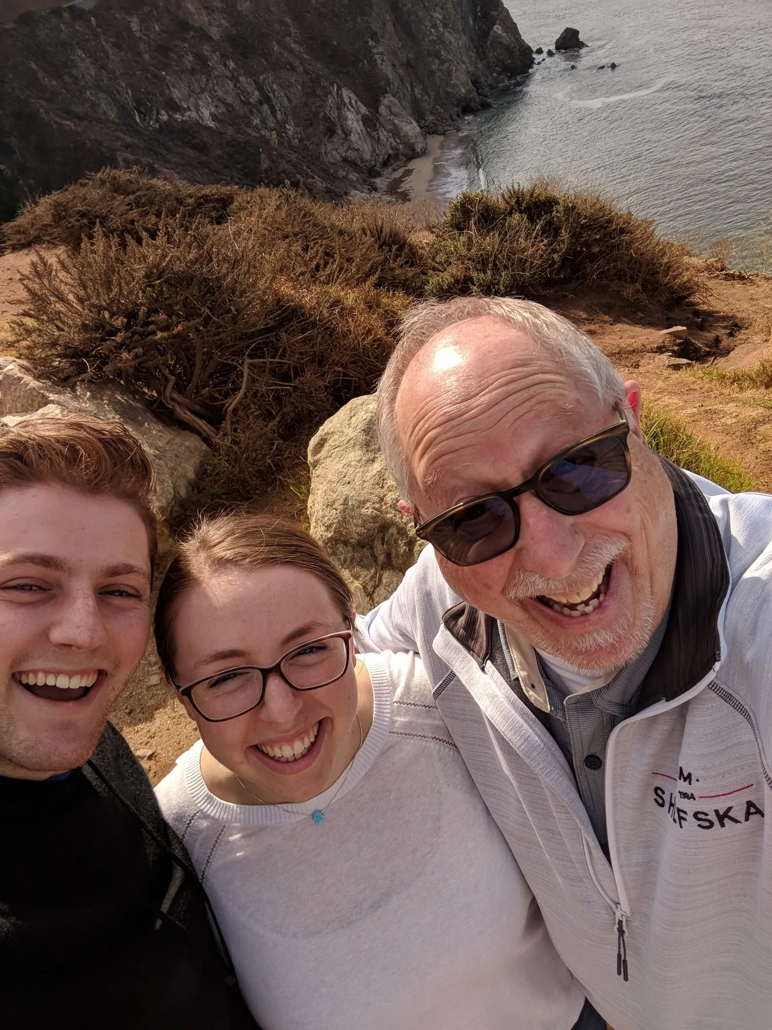 Zach, Dara and Ray together on a windswept cliff above the ocean
